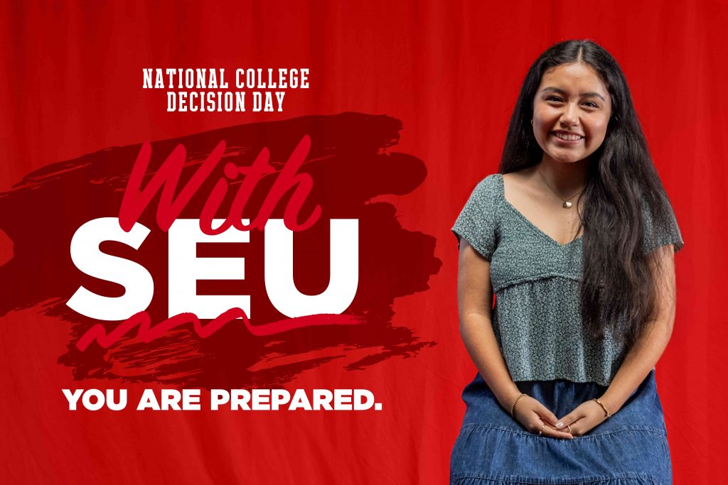 Reina, a student at SEU, smiling in front of a red backdrop.