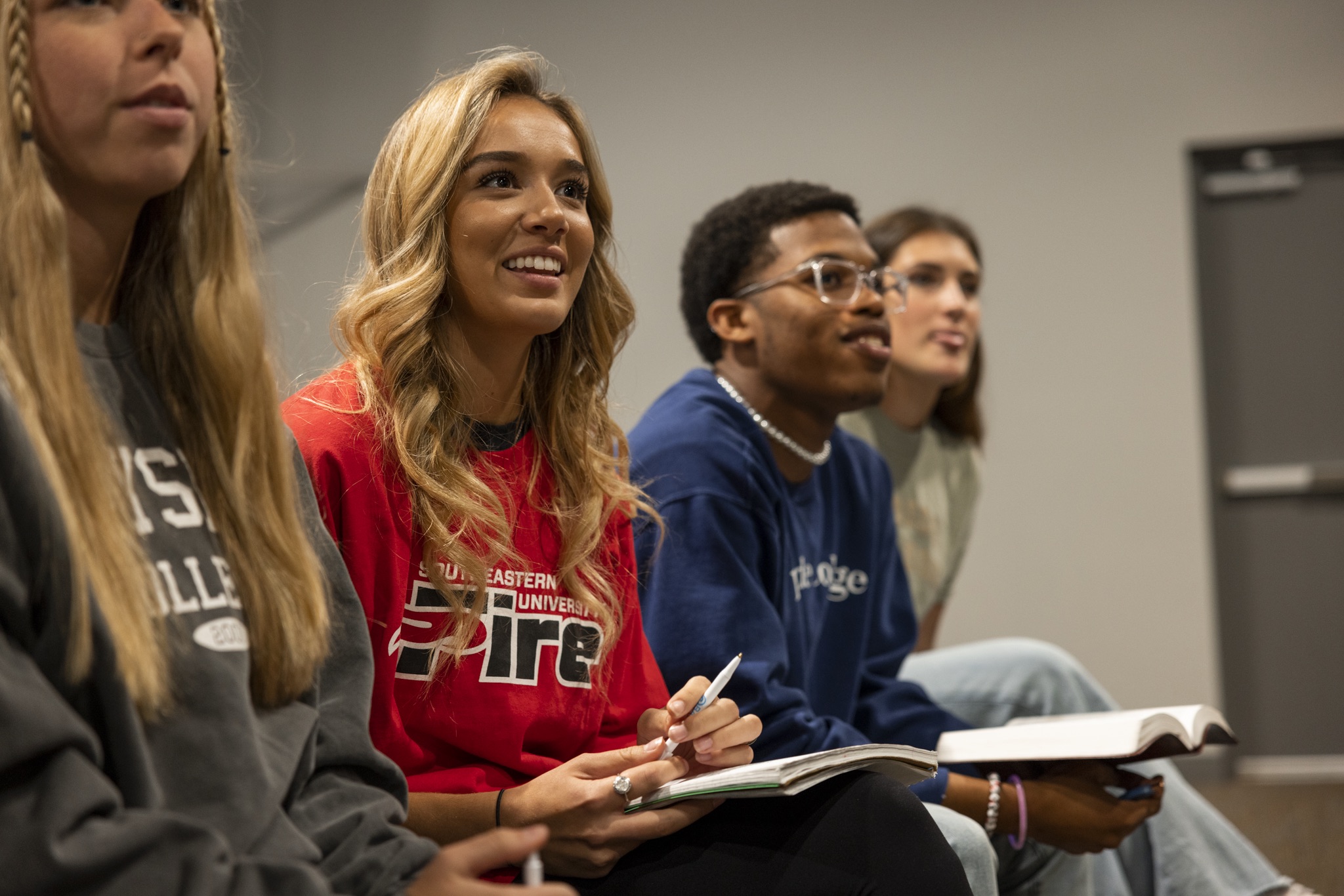 Student smiling while in lecture wearing red SEU crewneck