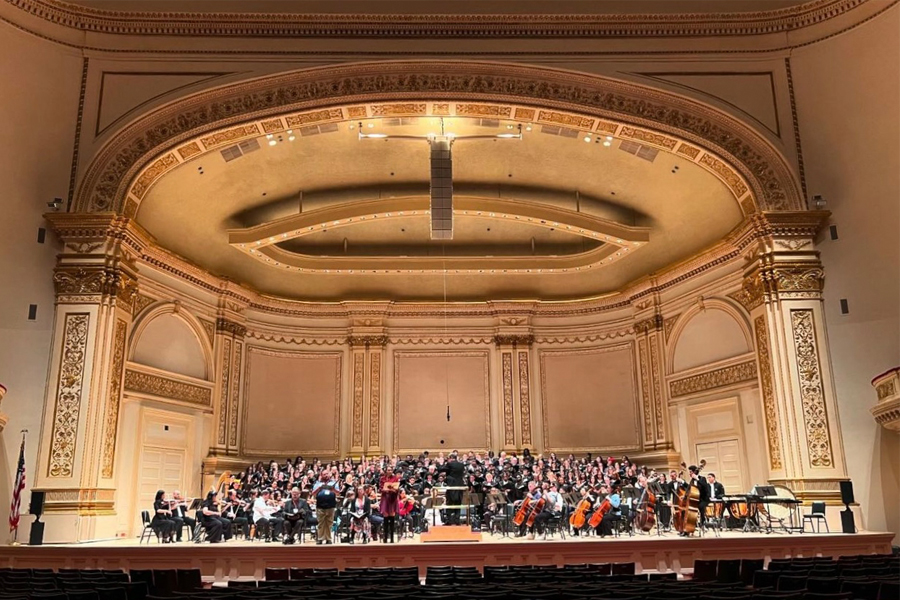 A wide shot of a large group of music students on the stage at Carnegie Hall in New York City