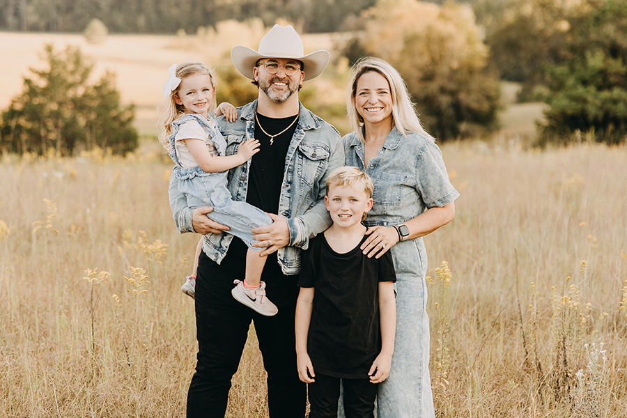Christian Leaphart with her husband and two children standing in a field.