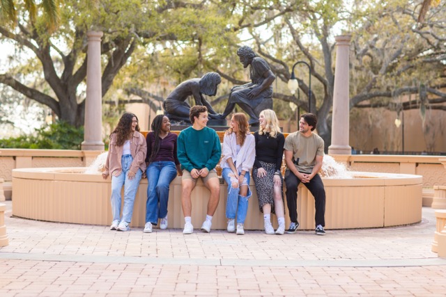 Students outdoors sitting by the Jesus Fountain on campus