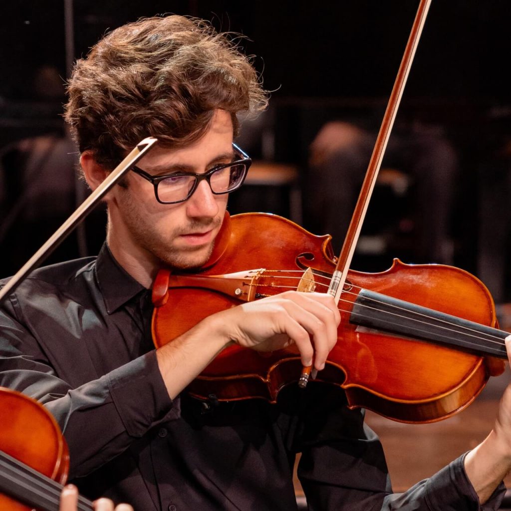 Student playing violin at a music concert