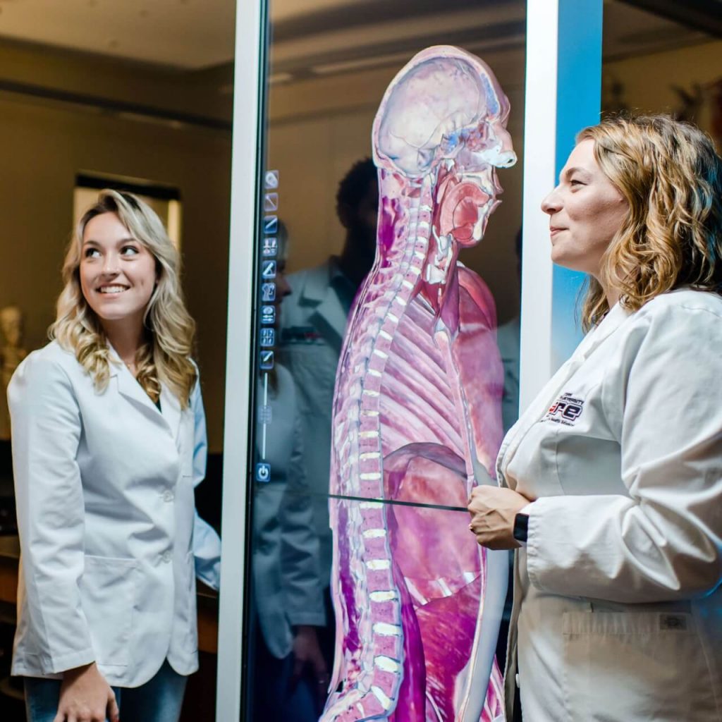 Student in front of a medical simulator with professor