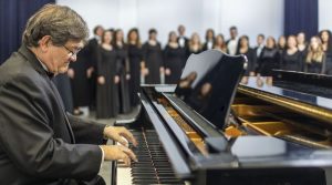 Man in dressed in classic attire accompanying choir