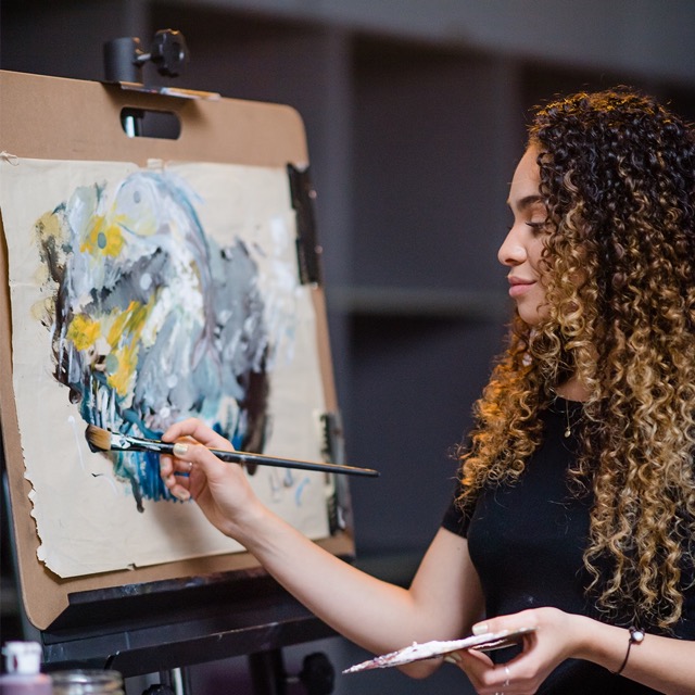 Female student painting on an easel 