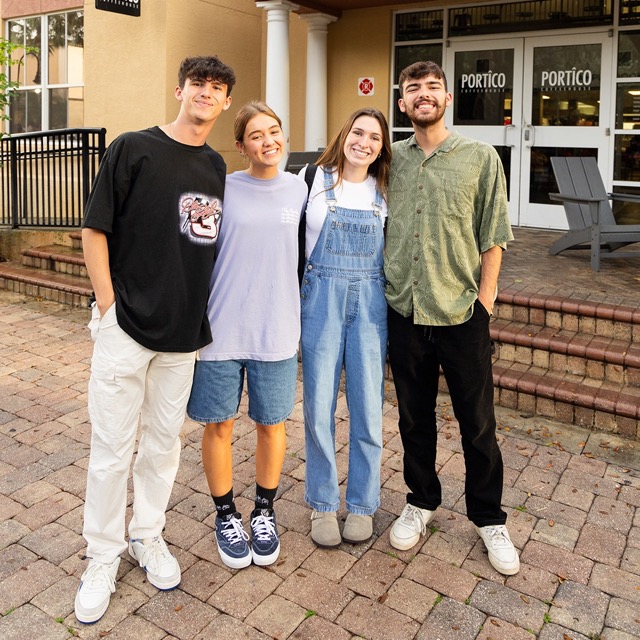 Four students smiling standing in front of Portico Coffeehouse