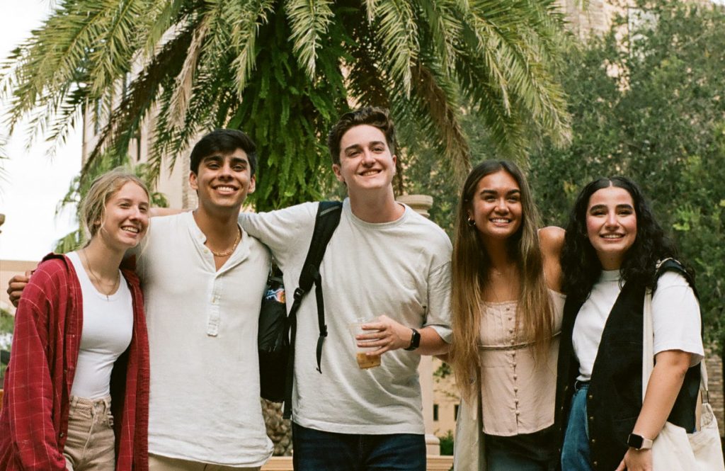 Five students smiling for a photo on campus