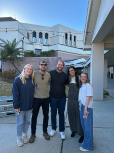 Ray standing in front of a building with other people. 