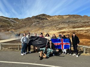 Students smiling and laughing while holding Iceland flag