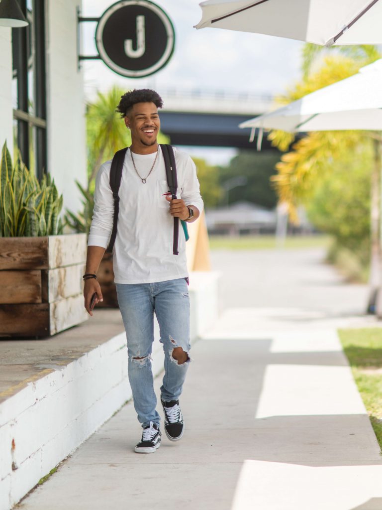 A young man with a backpack walks outside of the Joinery Food Hall in Lakeland, Florida.