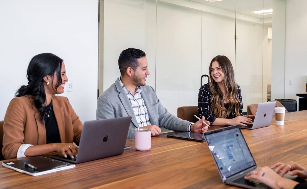 Three people sitting at a conference table working and discussing together.