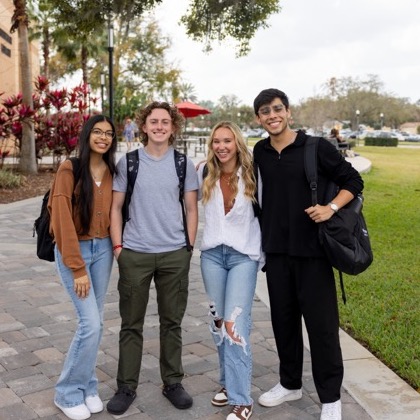 Group of four students smiling on campus