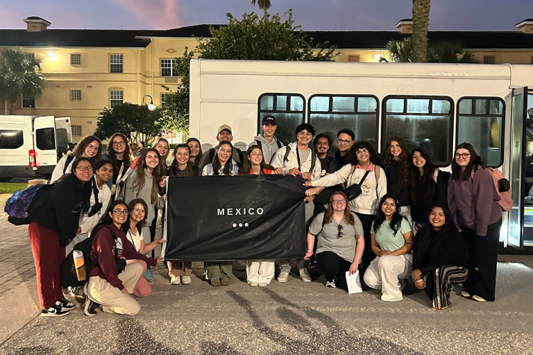 Group of students standing together holding a "Mexico" flag.