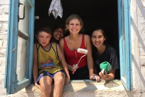 Perri Morales standing with others holding a paint roller