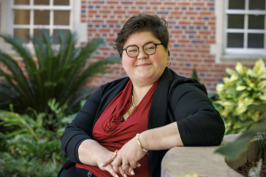 Rachel Ward Boatwright is smiling at the camera and leaning against a wall outdoors.