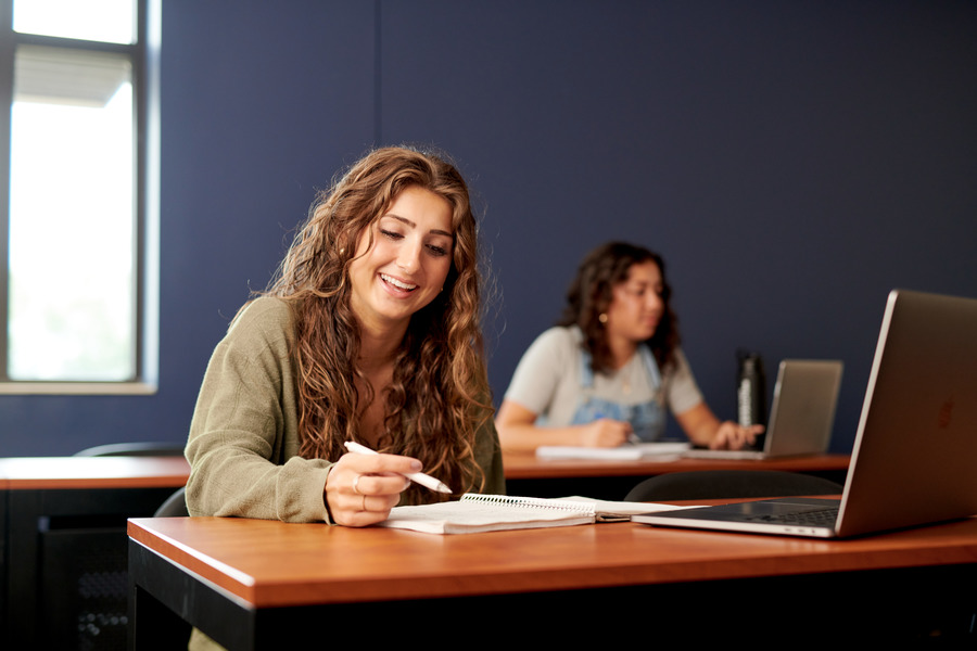 Two girls in a classroom studying.