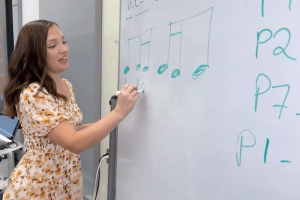 Sierra Yoder writes music notes on a classroom white board