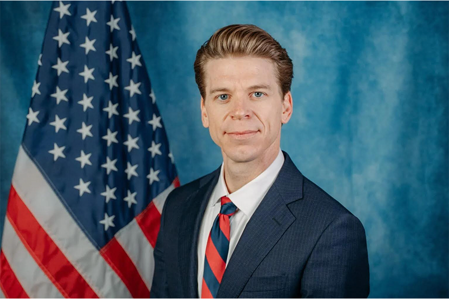SEU Alumnus Austin Rogers posing in front of American Flag