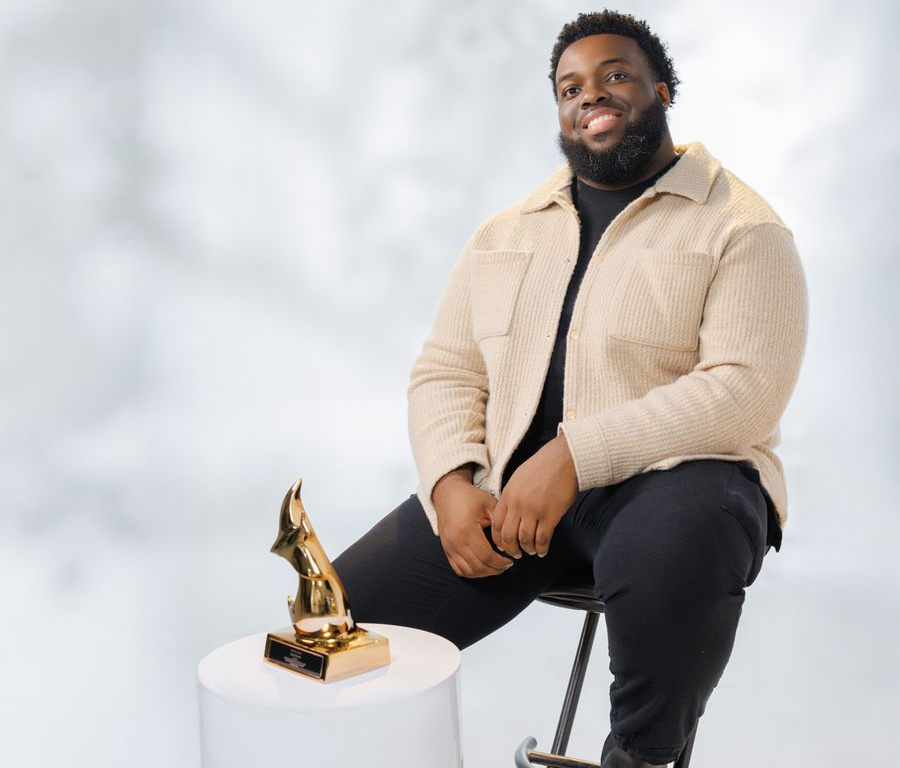 Sam Simon is sitting on a chair. His Dove Award trophy is on a low table in front of him.