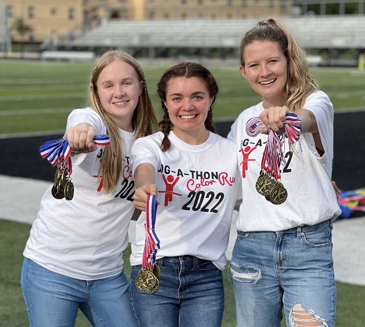 Three female students holding medals at an on-campus event