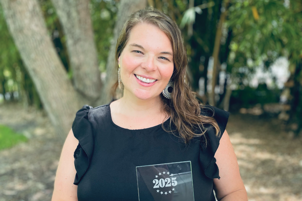 Dr. Megan Hudson standing outside holding an award.