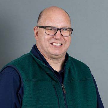 Headshot of a man in front of a gray background.