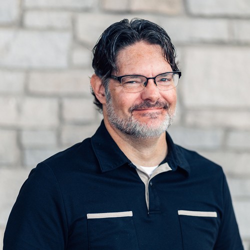 Headshot of a man in front of brick background.